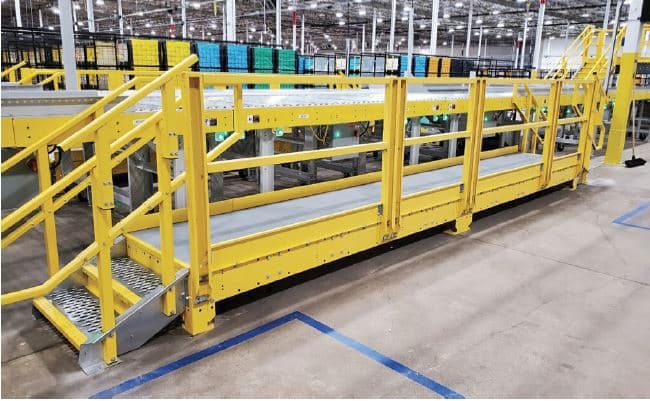Yellow industrial access platform with stairs and guardrails beside process equipment.