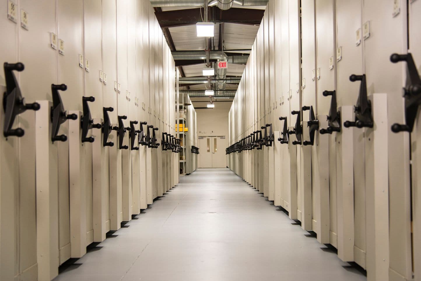 Long central aisle between high-density mobile shelving carriages holding records in a managed facility