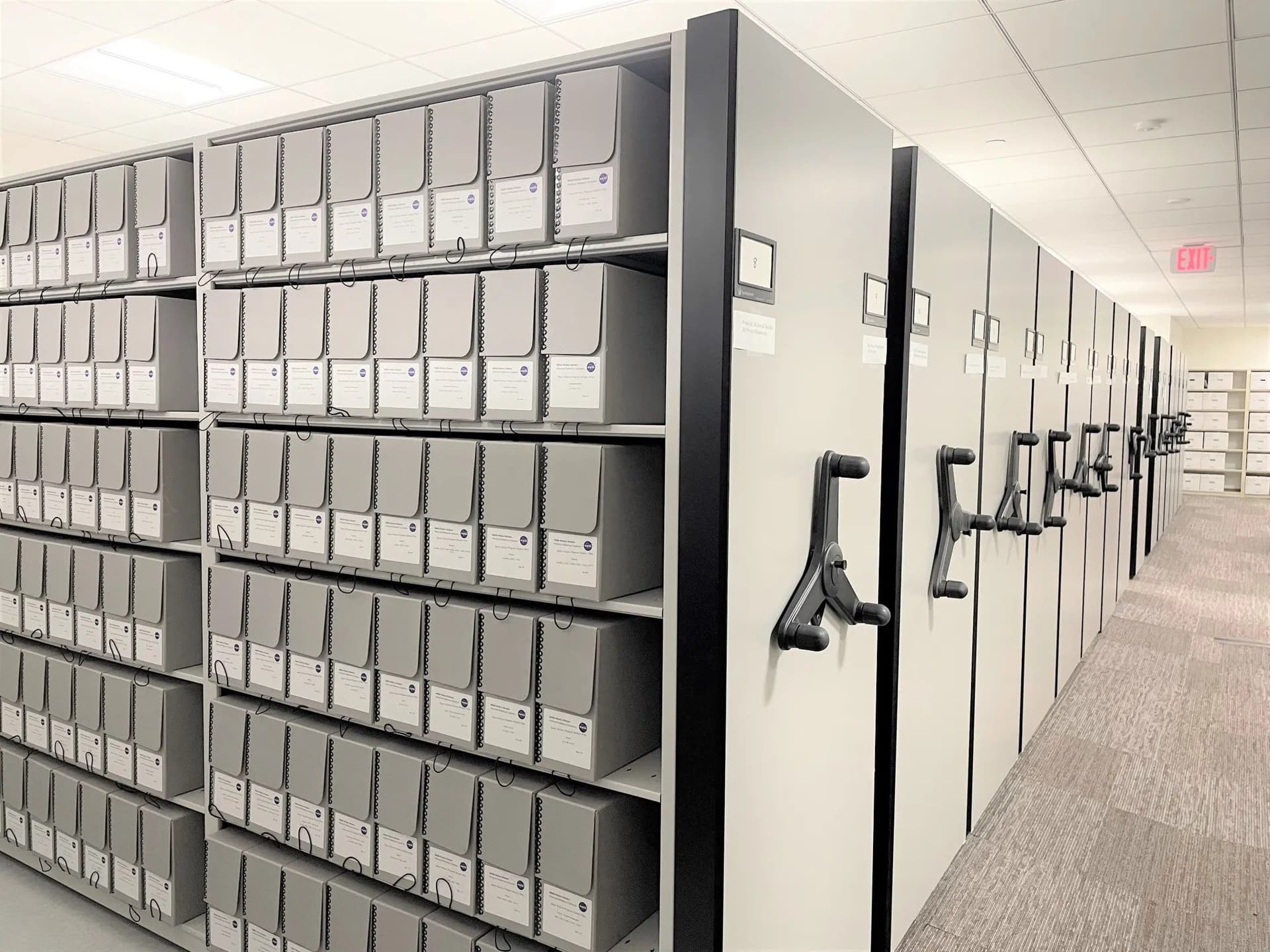 Rows of labeled archive boxes on mobile shelving units in a managed records room