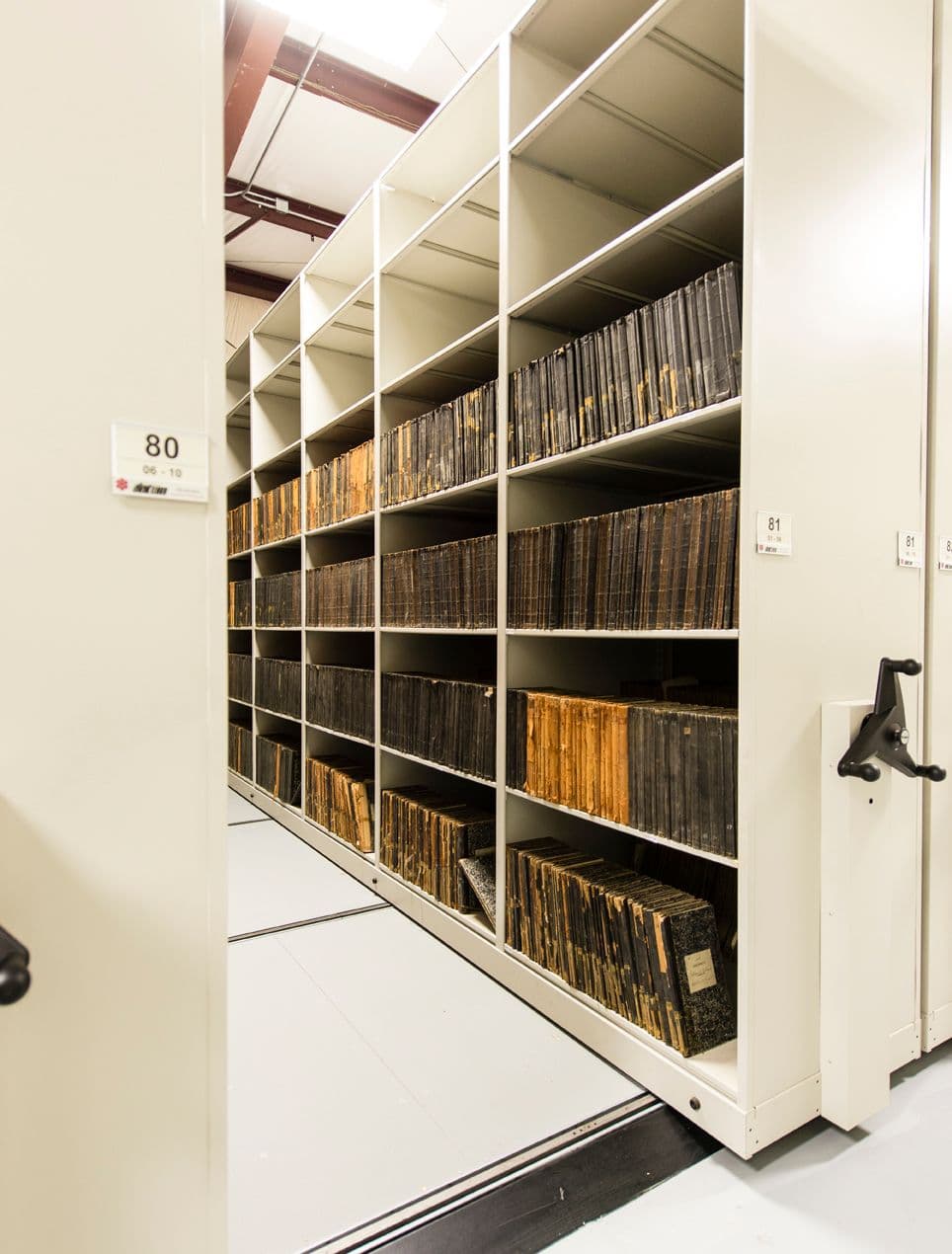 Rows of archive boxes on high-density mobile shelving in a large records facility